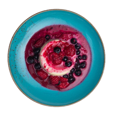 top view of a panna cotta on a plate with berries drizzled on top